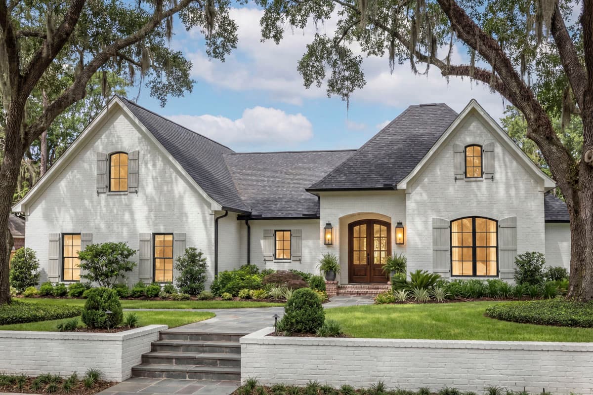 House plan exterior: Modern farmhouse style, one story, white brick, gabled dormers, arched entry with double doors, and metal-clad windows.