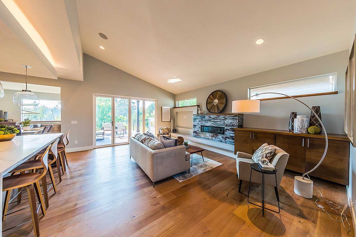 Interior view of a great room with vaulted ceiling, fireplace, and large sliding glass doors leading to a patio.