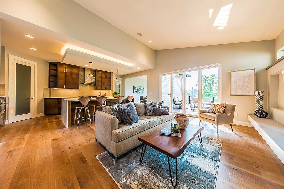 Open concept living area and kitchen with a large sofa, coffee table, island with bar stools, and sliding glass doors to patio.