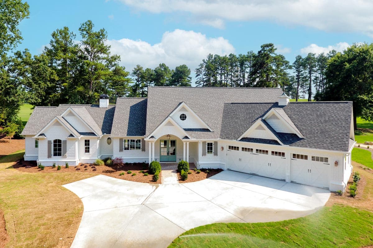Modern Farmhouse house plan exterior with a white facade, gabled dormers, a covered porch, and a triple-car garage.
