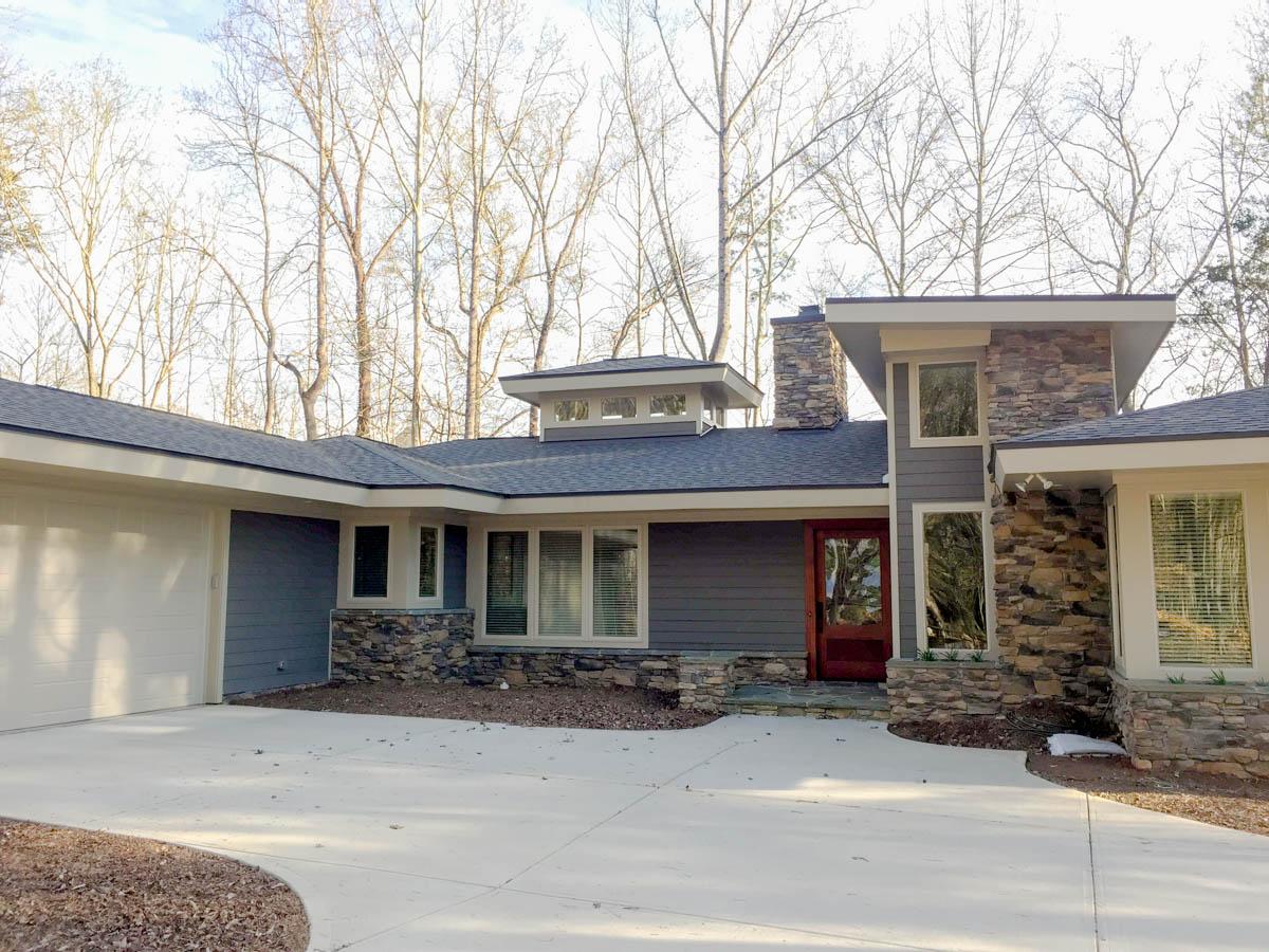Modern house plan exterior with stone accents, wide eaves, horizontal siding, and a prominent chimney.