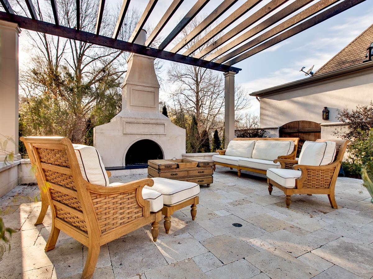 Outdoor patio with a large fireplace, pergola, and seating area. House plan exterior.