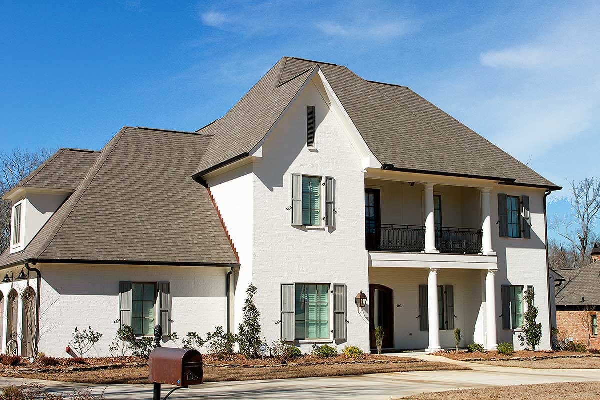 House plan exterior. Two-story home with a gabled roof, a front porch with columns, and a dormer. Features gray shutters.