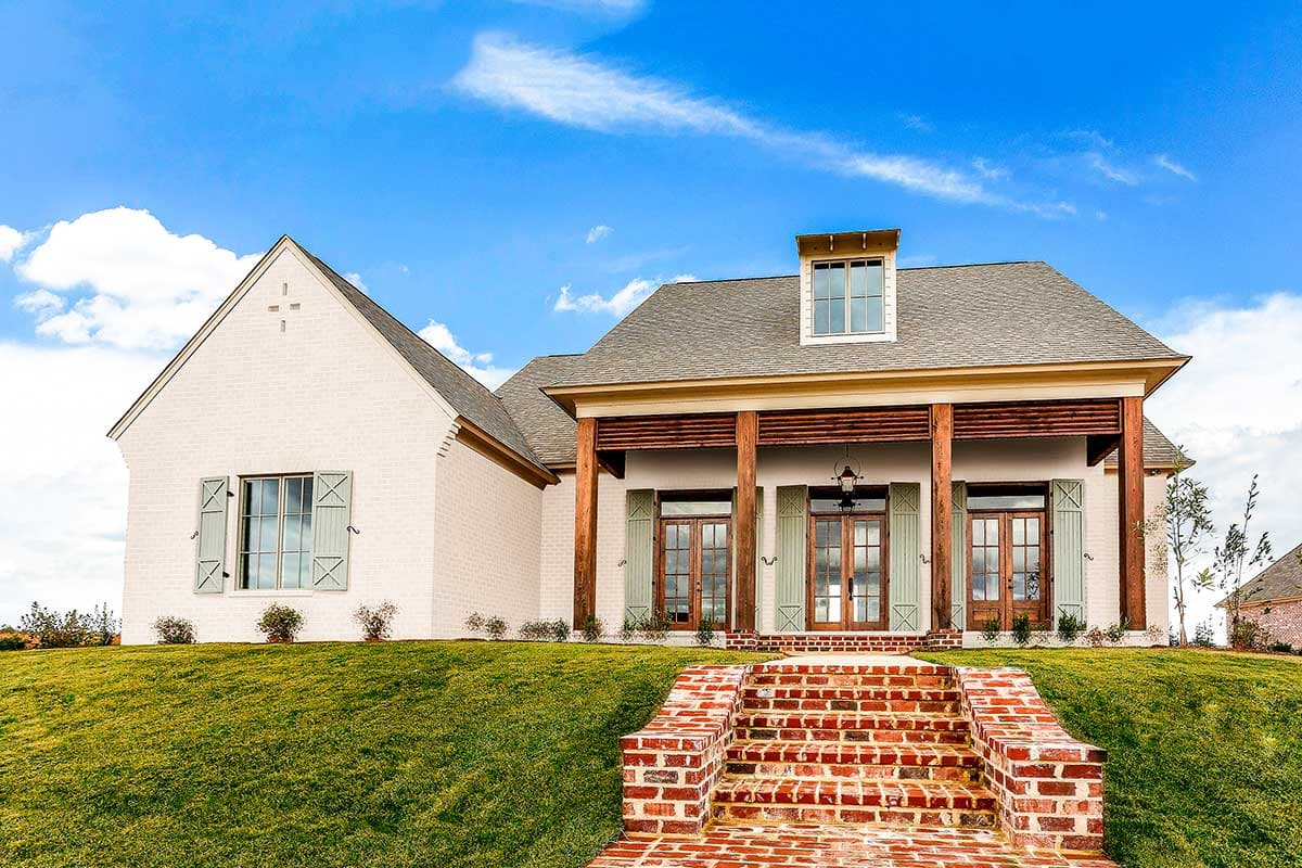 House plan exterior featuring a two-story design with a front porch, gables, and a dormer. Brick steps lead to the entrance.
