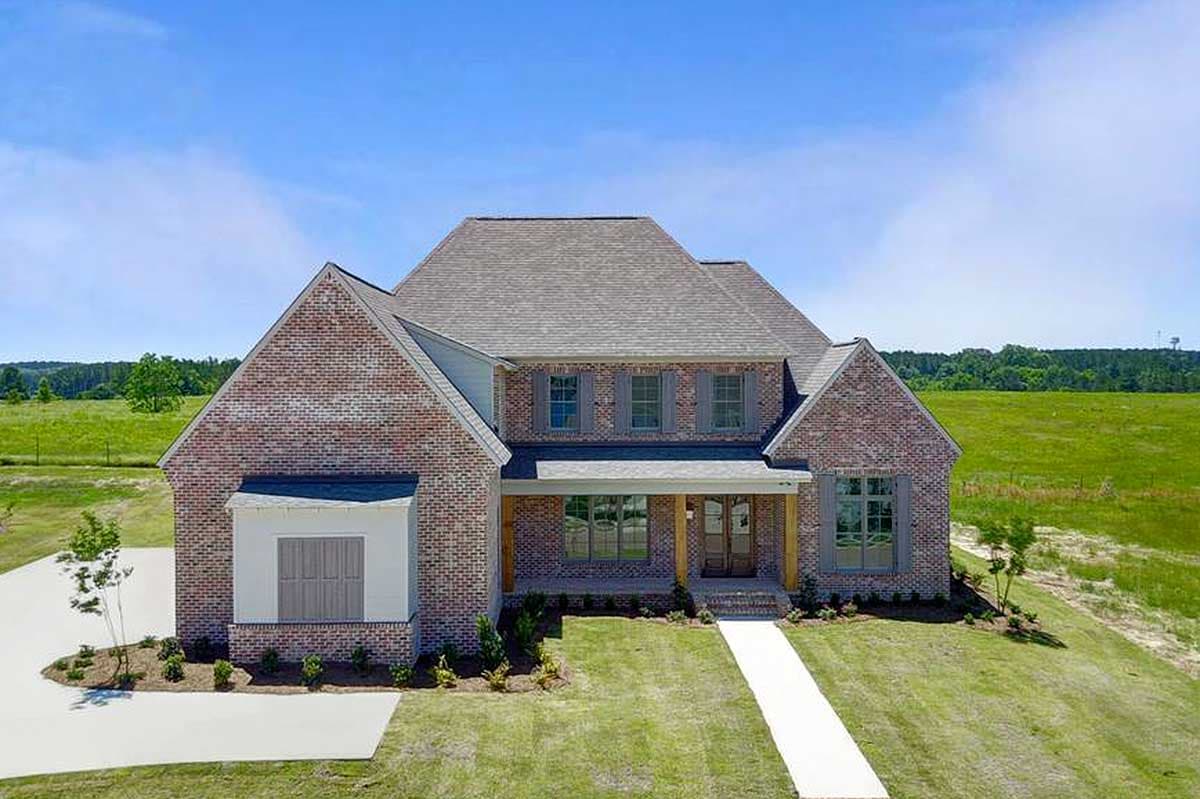 House plan exterior. Two-story brick home with gabled roof, front porch, and dormers. Features include a side-entry garage.