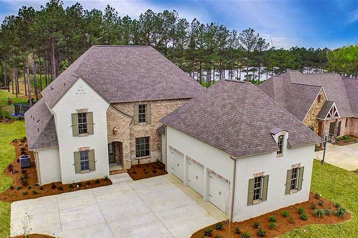 House plan exterior: Two-story home with brick accents, dormer, and attached three-car garage.