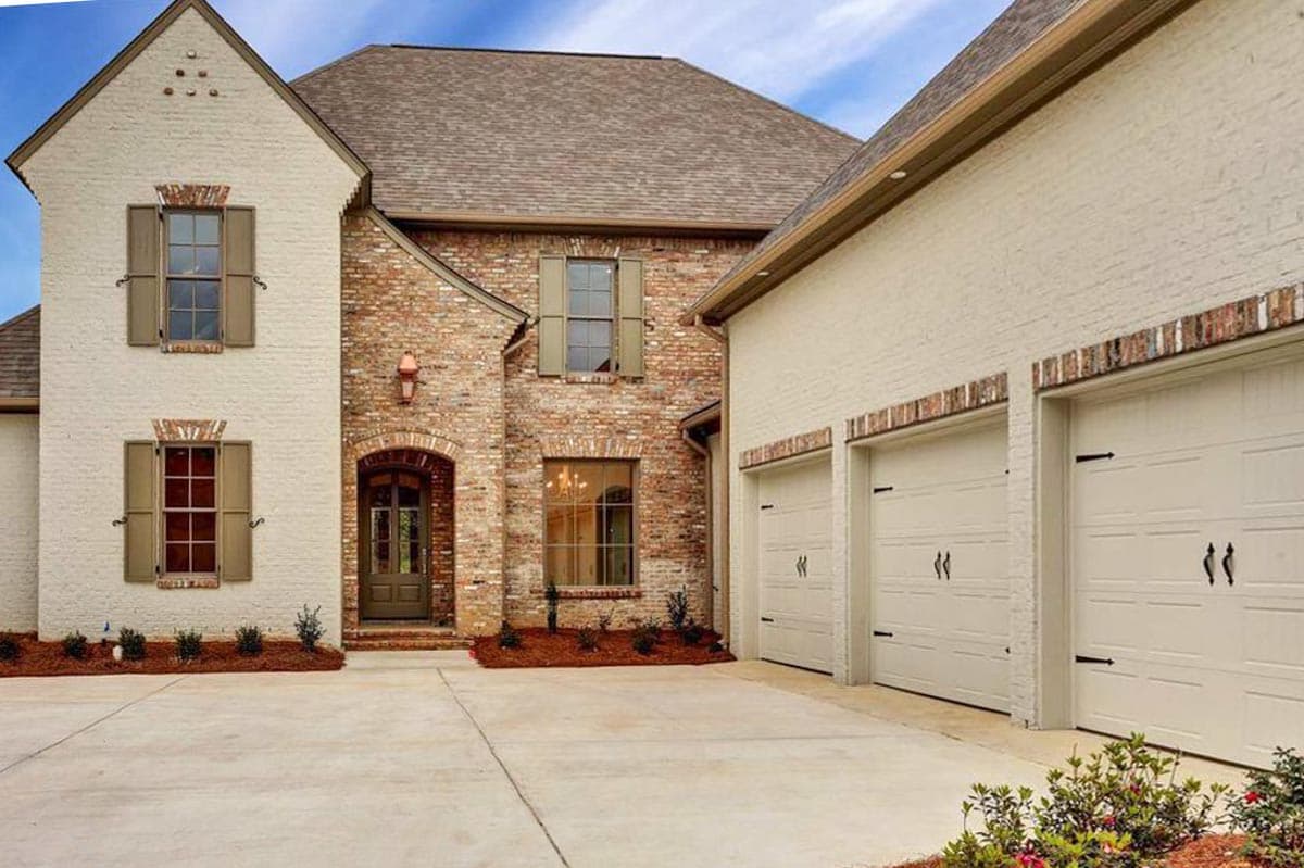House plan exterior: two-story home with brick and painted brick exterior, arched entryway, gable roof, and three-car garage.