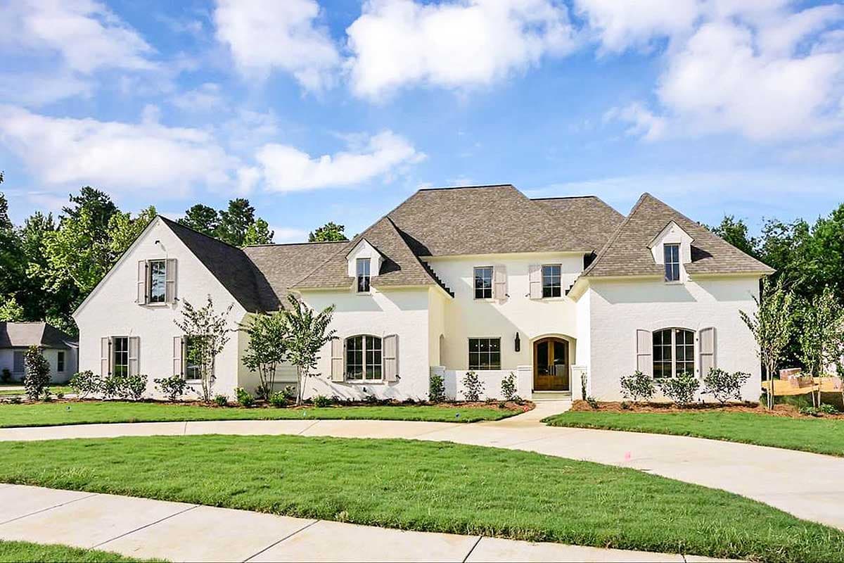House plan exterior with two stories. Features include multiple gables, arched windows, shutters, and a front entry with a wood door.