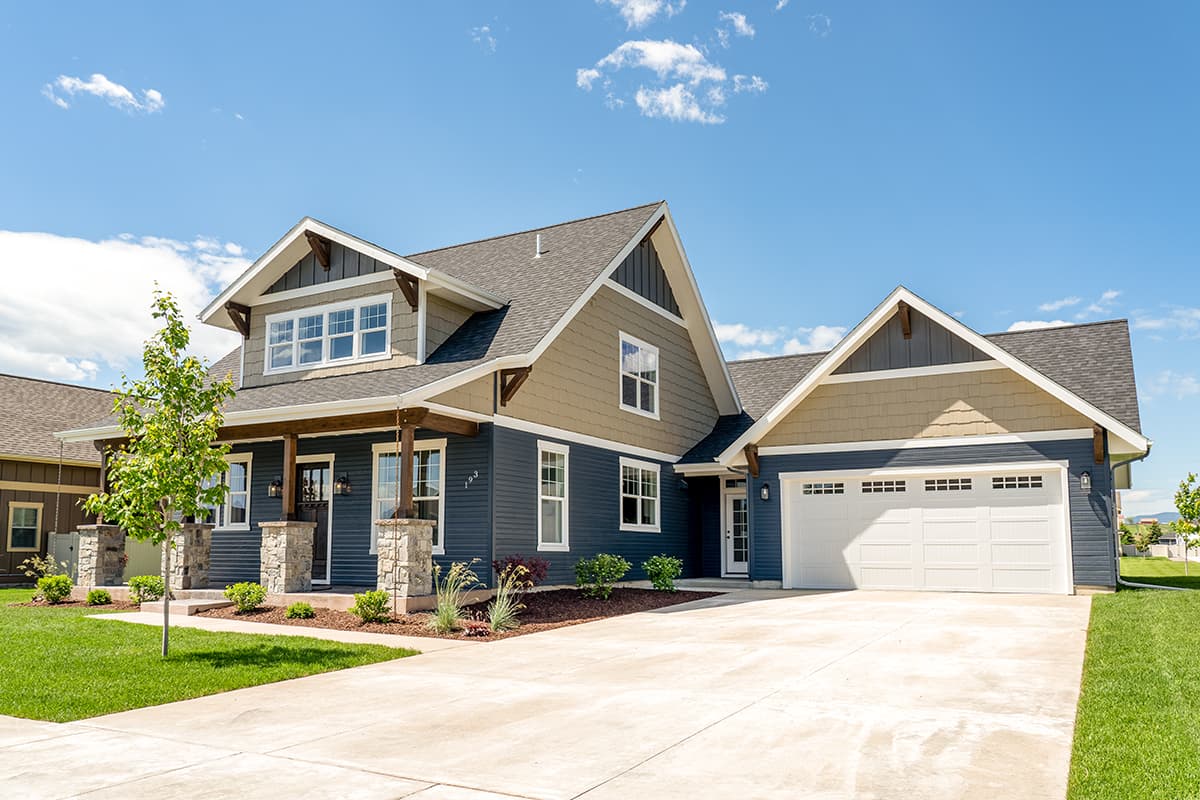 House plan exterior. Two-story Craftsman home with gabled rooflines, a front porch with stone columns, and an attached garage.