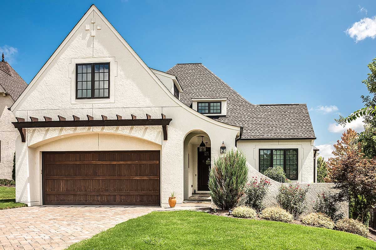 House plan exterior: White stucco, arched garage, gabled dormer, and steep hip roof.
