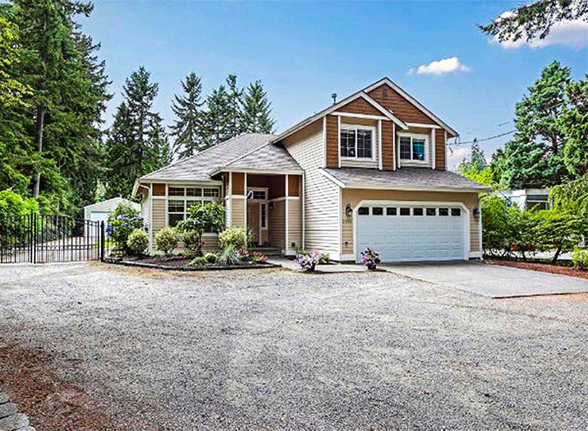 House plan exterior. Two-story home with a gabled roof, dormers, and an attached garage. Features include a covered front porch and a paved driveway.