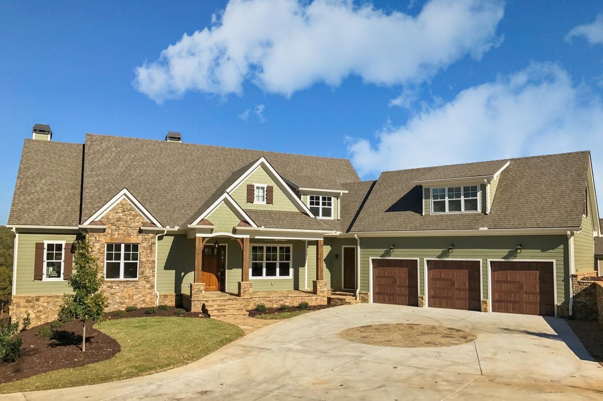 House plan exterior with Craftsman style, multiple gables, a front porch, stone accents, and a three-car garage.