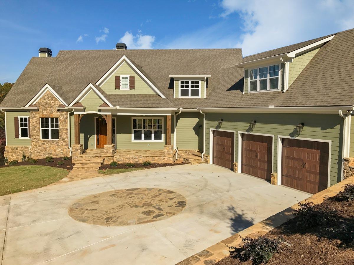House plan exterior with stone accents, covered entry porch, multiple gables, and a three-car garage.