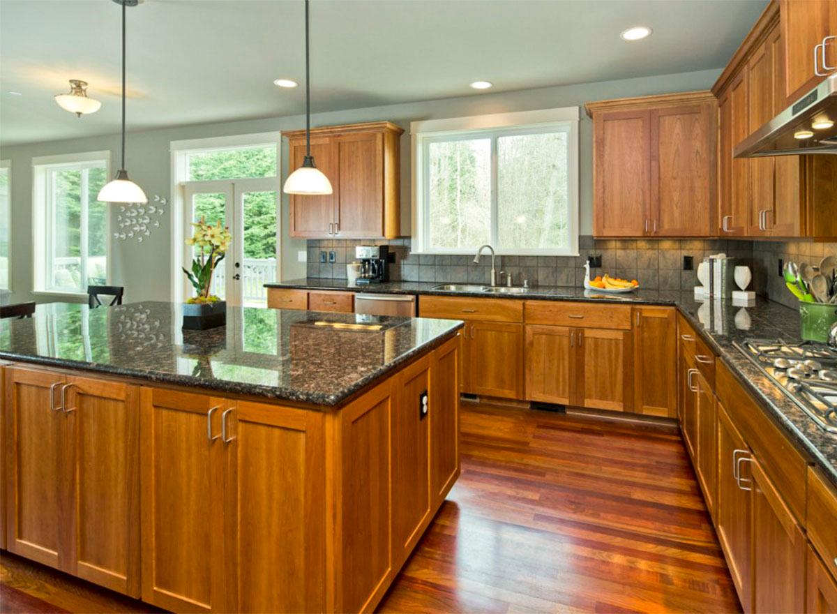 Kitchen featuring a large island, granite countertops, wood cabinetry, and stainless steel appliances.
