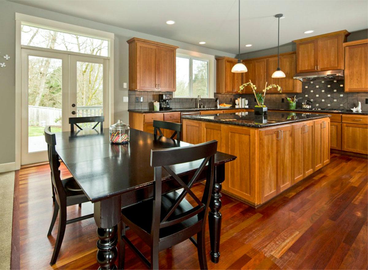 Kitchen with island, wood cabinetry, granite countertops, and dining area with french doors to the exterior.