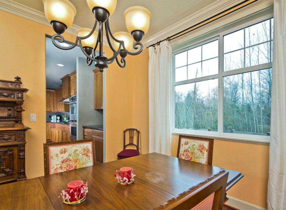 Dining room interior view through doorway to kitchen; large window with treeline view.