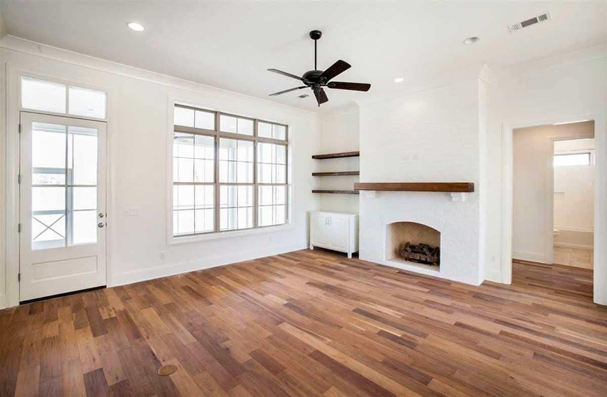Interior view of a living room with a fireplace, large window, glass door, and wood floors.