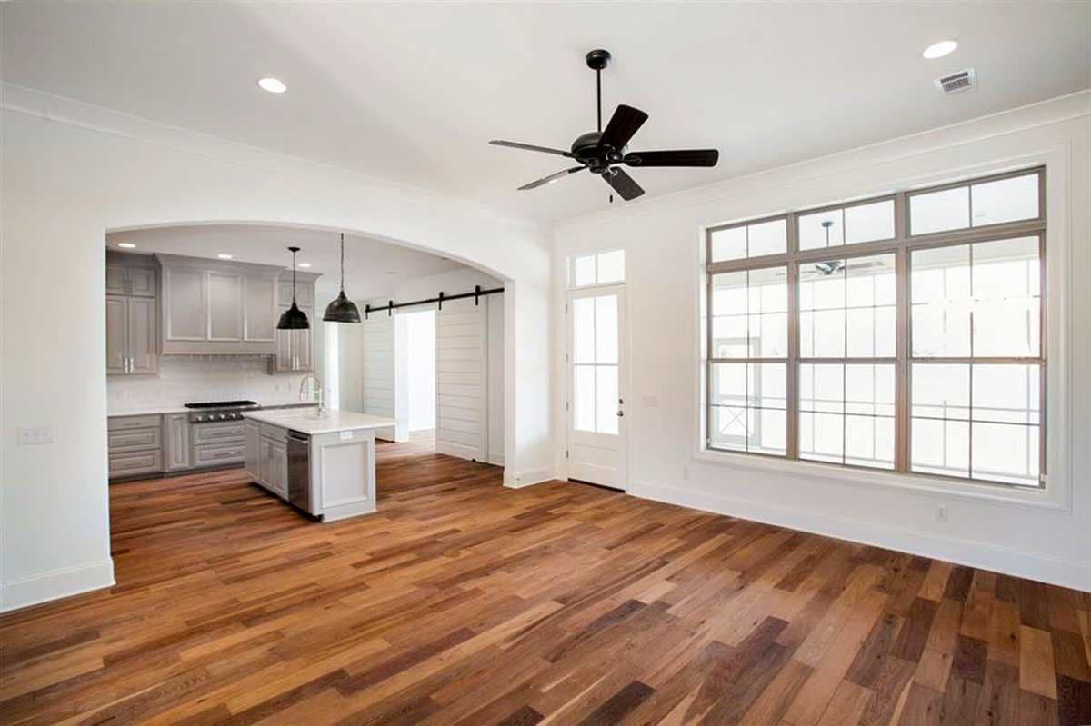 Open layout showing kitchen with island and great room with large multi-pane window. Barn door visible.