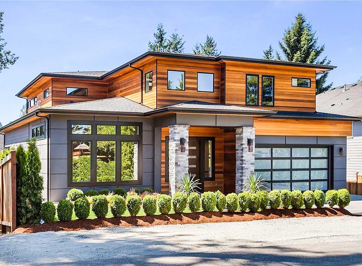 Modern house plan exterior with wood and grey siding, flat roofline, large windows, stone-clad columns, and glass garage door.