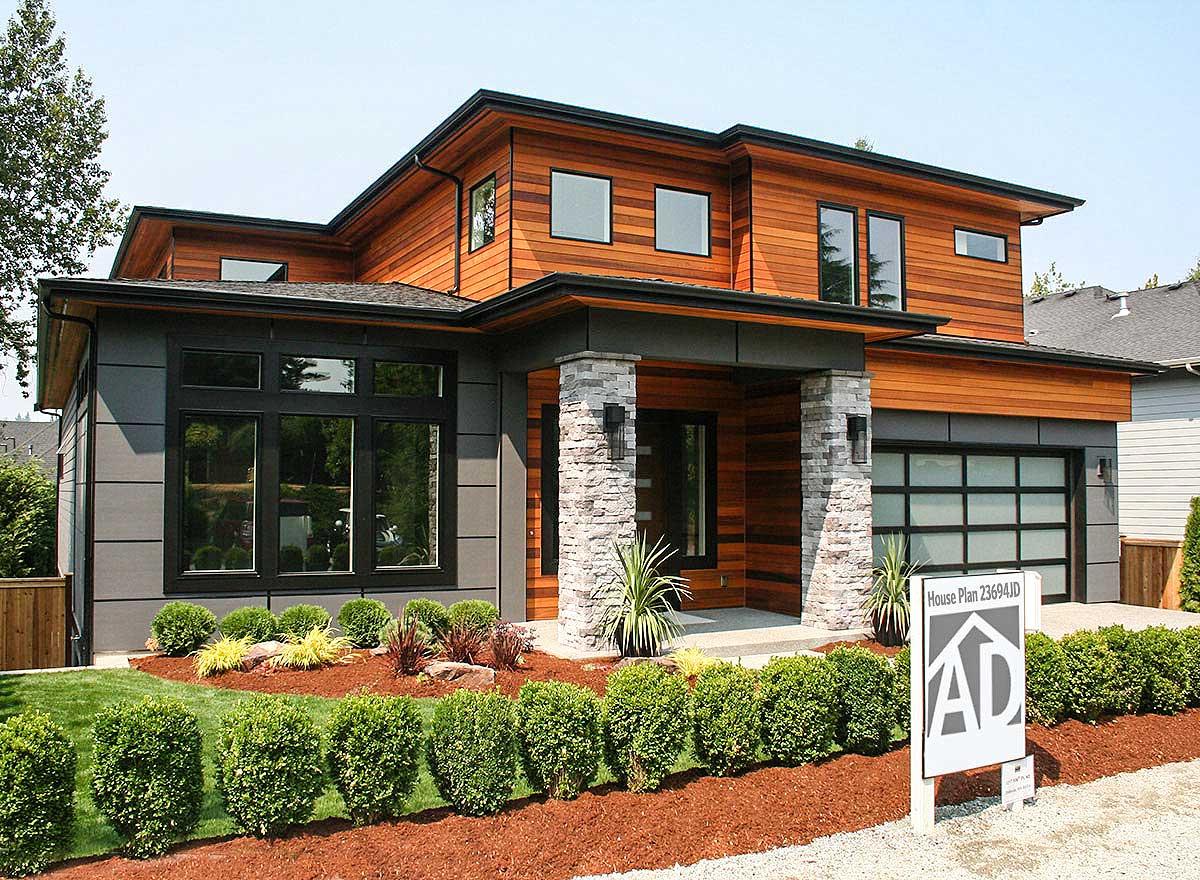 Modern house plan exterior with wood siding, stone accents, large windows, and a glass garage door.
