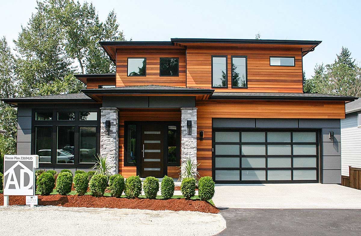 Modern two-story house plan exterior with wood siding, stone accents, flat roof, and glass garage door.