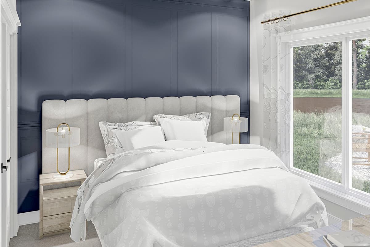 Bedroom with paneled blue wall, king bed, and large window overlooking backyard with trees and water.