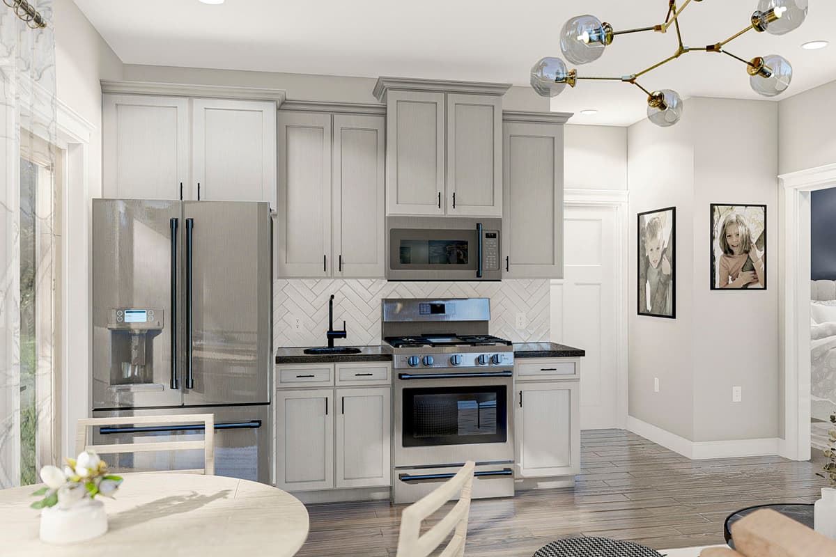 Kitchen with stainless steel refrigerator, gray cabinetry, gas range, microwave, herringbone tile backsplash, and black granite countertops.
