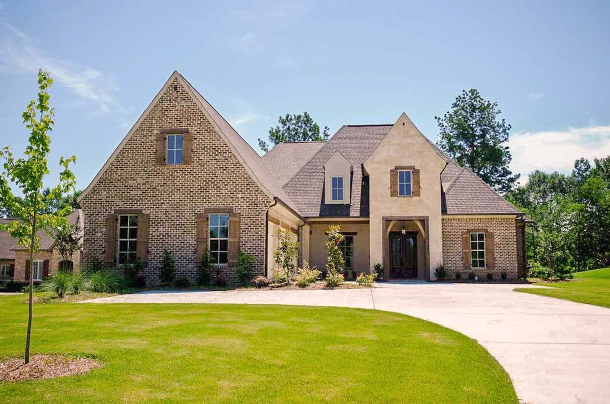House plan exterior featuring brick and stucco facade, gabled rooflines, and dormers. The house has a two-car garage, and shuttered windows.