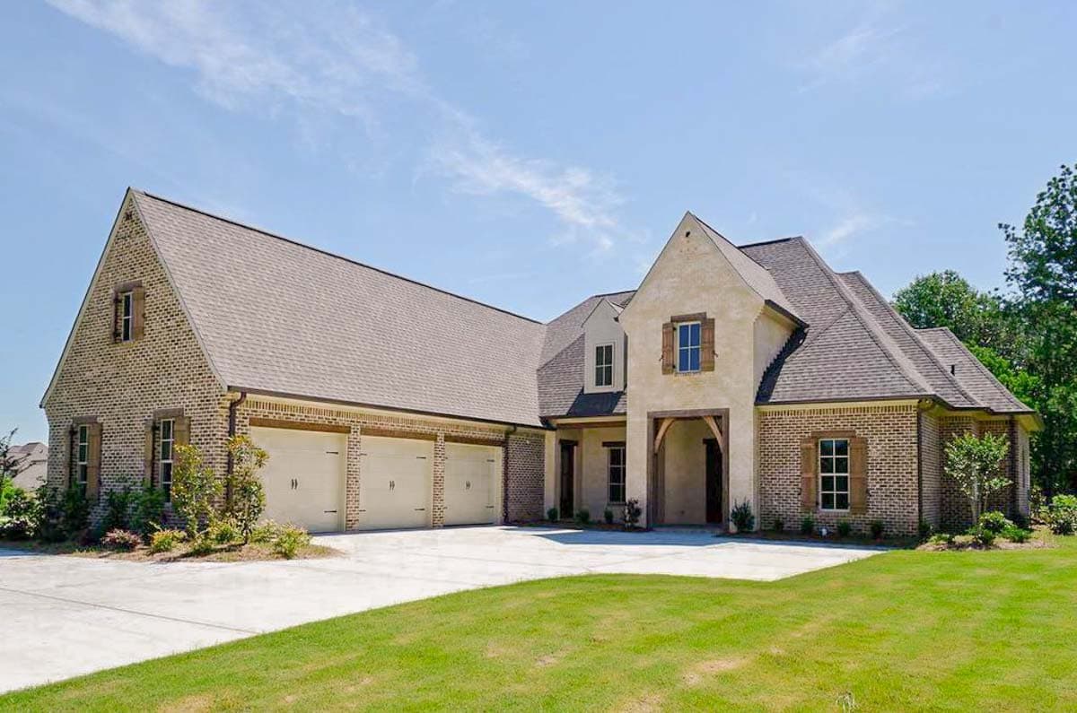 House plan exterior featuring brick facade, three-car garage, arched entry, and multiple gables.