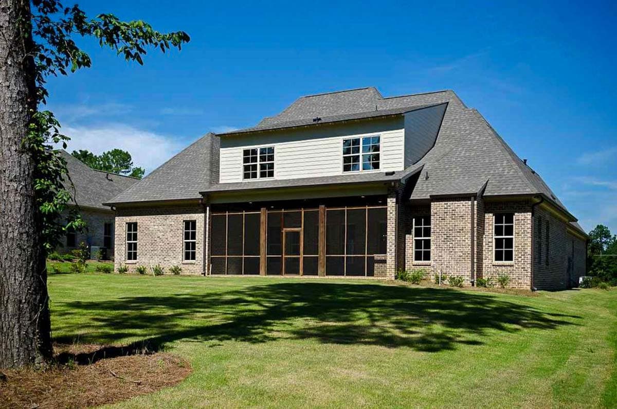 House plan exterior with brick facade, screened porch, dormer windows, and hip roof.