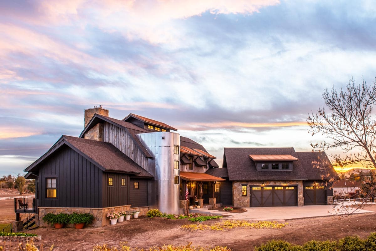 House plan exterior with board and batten siding, multiple gabled rooflines, a stone chimney, and a three-car garage.