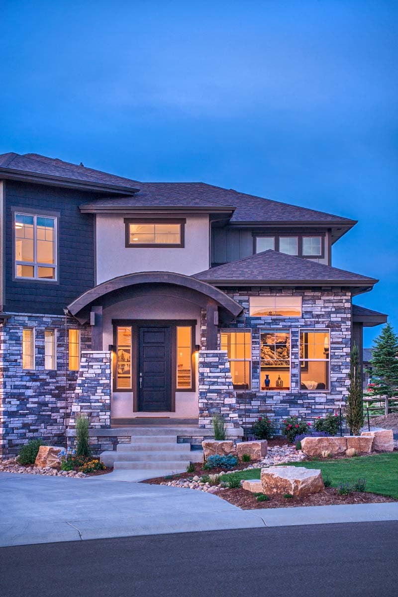 Two-story house plan exterior with stone facade, arched covered entry, and multiple gables.
