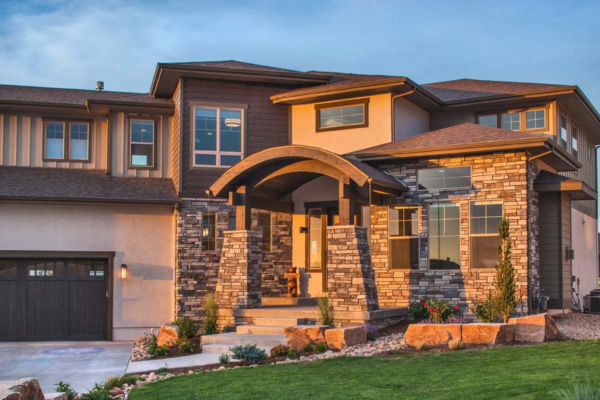 House plan exterior: Modern style, two-story, with stone accents, prominent arched covered entryway, and a detached garage.
