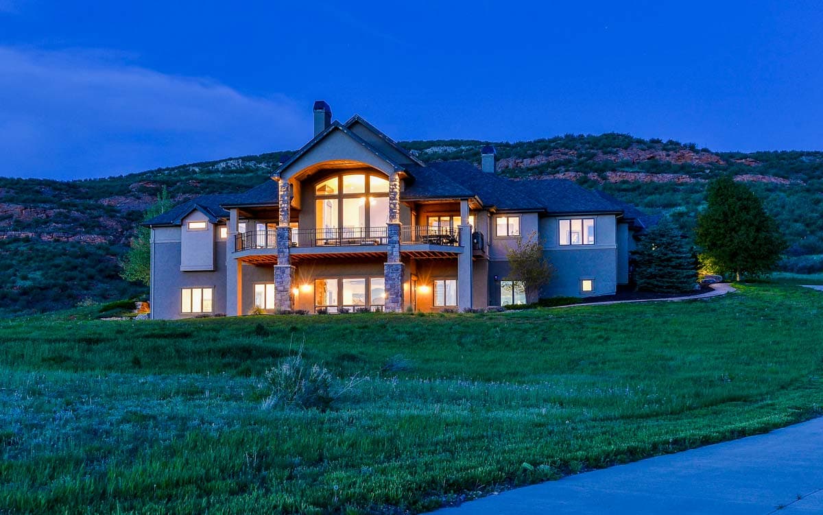 House plan exterior with a multi-story design, featuring arched windows, balconies, and stone-clad columns.