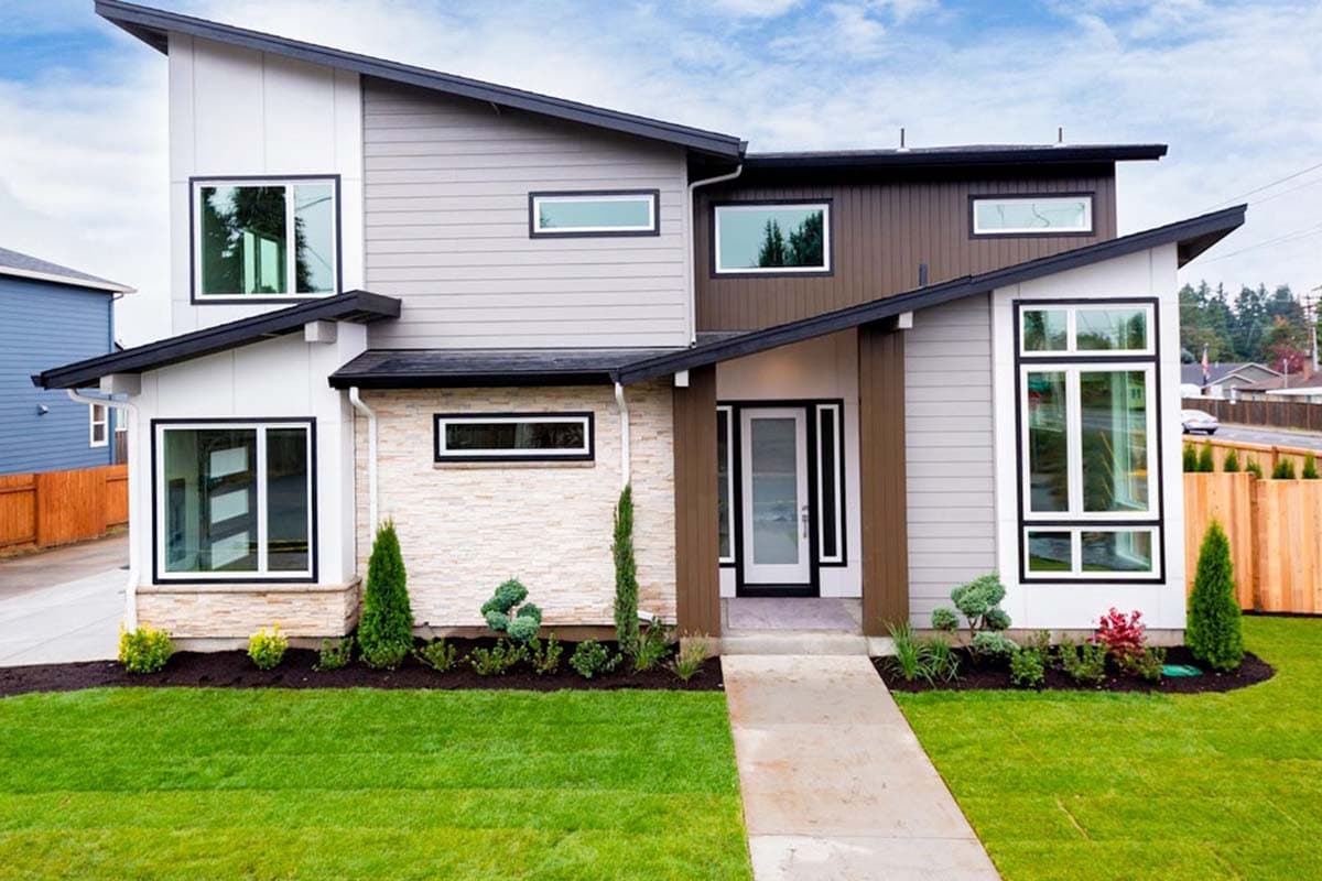 House plan exterior. Modern style, two-story home. Features include a sloped roof, large windows with black trim, and mixed siding materials.
