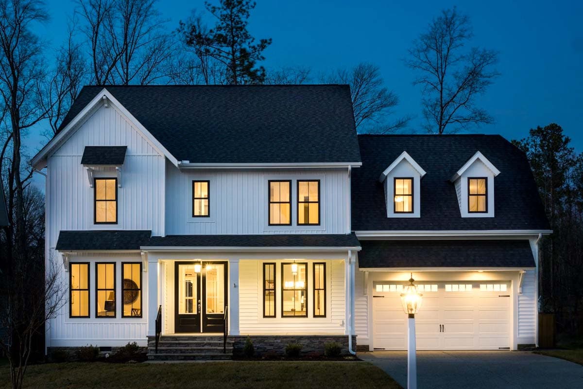 Modern Farmhouse two-story house plan exterior with a covered front porch, white vertical siding, gable dormers, and a two-car garage.