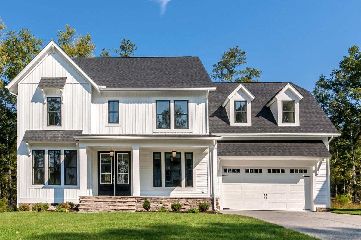 House plan exterior. Two-story Modern Farmhouse with gables, dormers, and a front porch. Features an attached garage and a vertical siding.