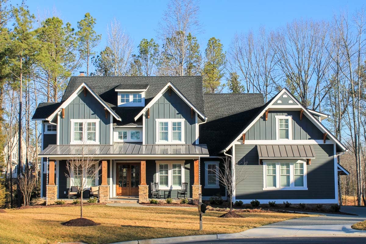Modern Farmhouse style house plan exterior, two stories, with a wrap-around porch, multiple gables, and dormers.