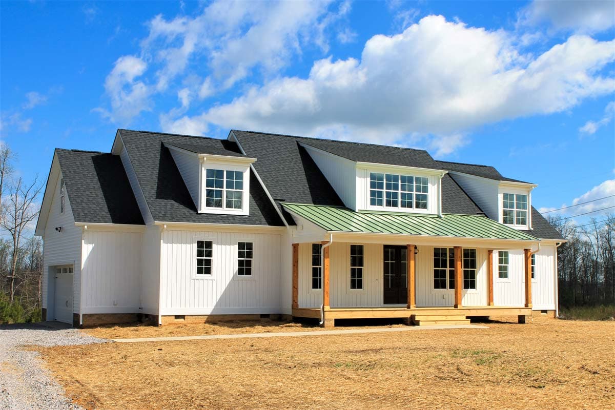 Modern Farmhouse style house plan exterior with white board and batten siding, dormers, and a green metal roof porch.