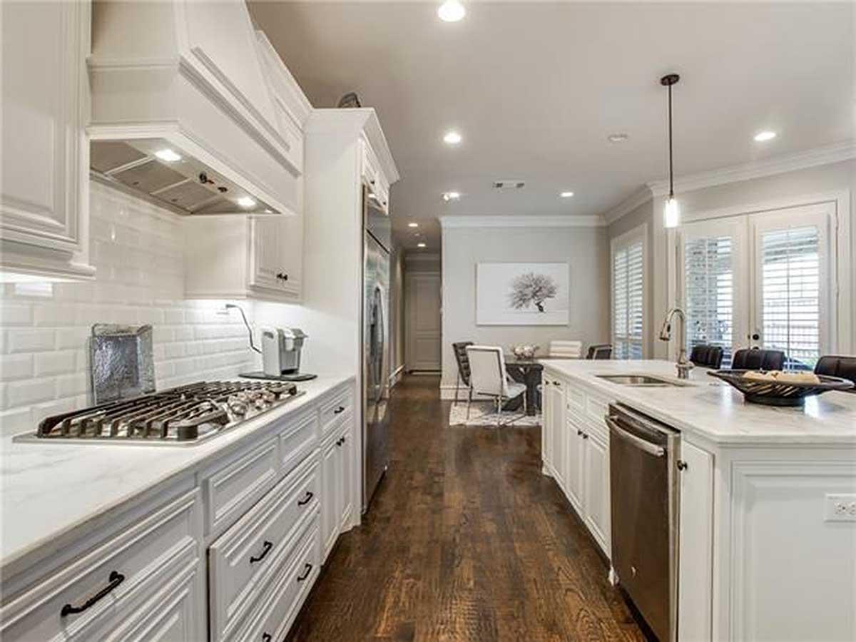 Modern kitchen with white subway tile backsplash, gas range, island with sink, and adjacent dining area.