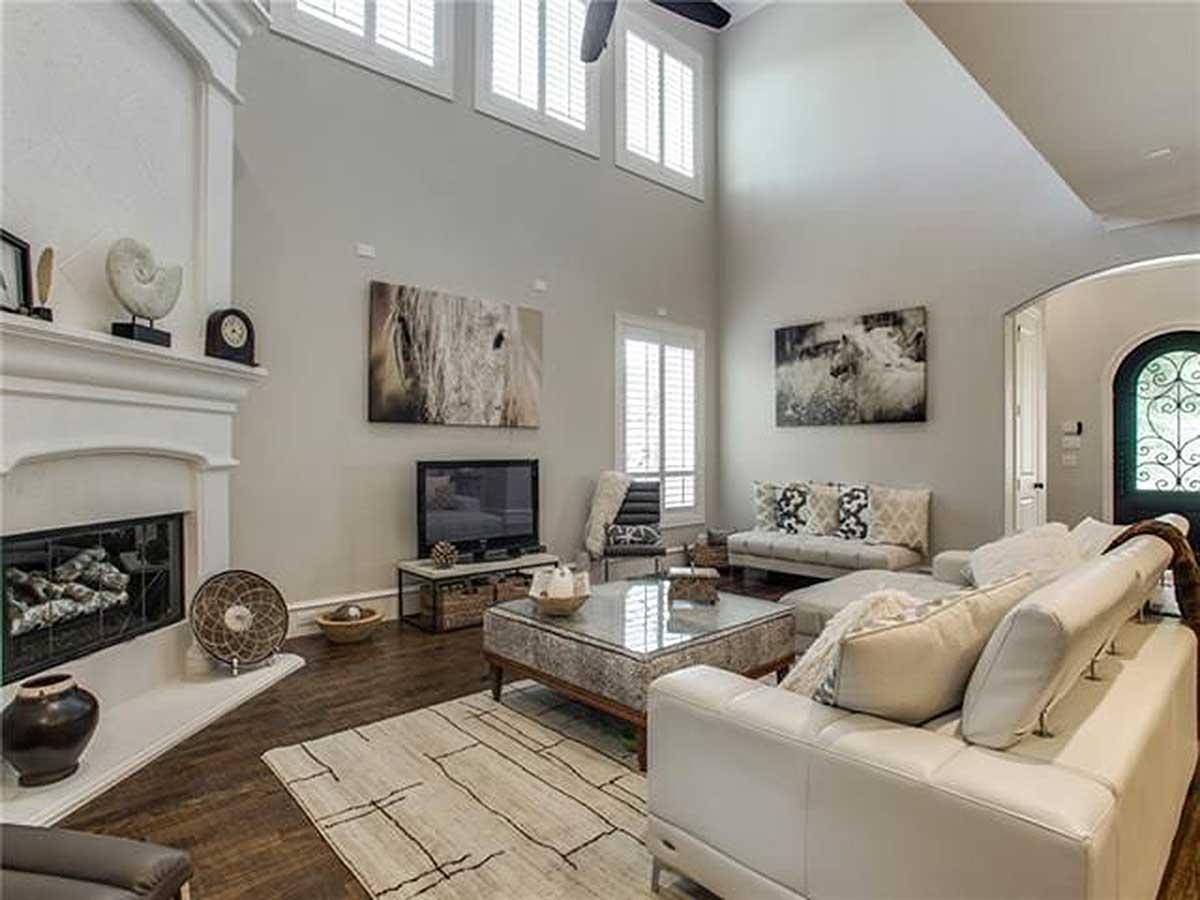 Great room with a fireplace, vaulted ceiling, and large windows with plantation shutters.
