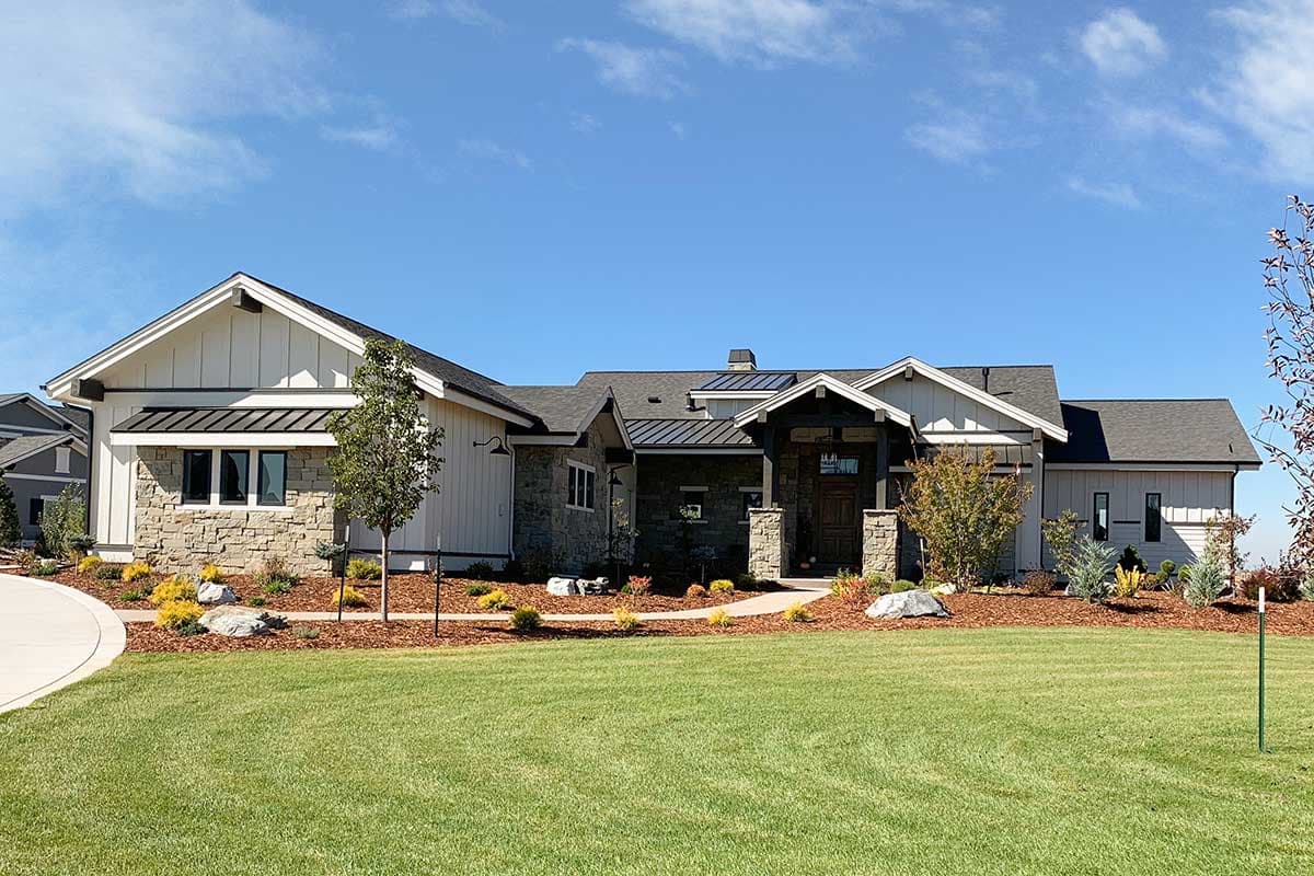 House plan exterior: Ranch style with stone and board-and-batten siding, prominent gables, and a covered entry.