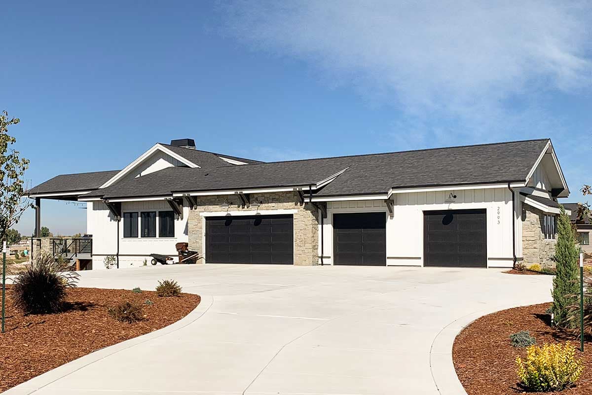 House plan exterior: Modern Farmhouse style, one story, with a covered porch, stone accents, and a three-car garage.