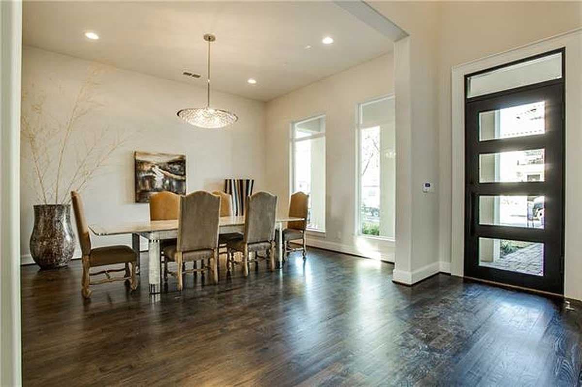 Dining room with a rectangular table, upholstered chairs, large windows, and a contemporary glass-paneled door.