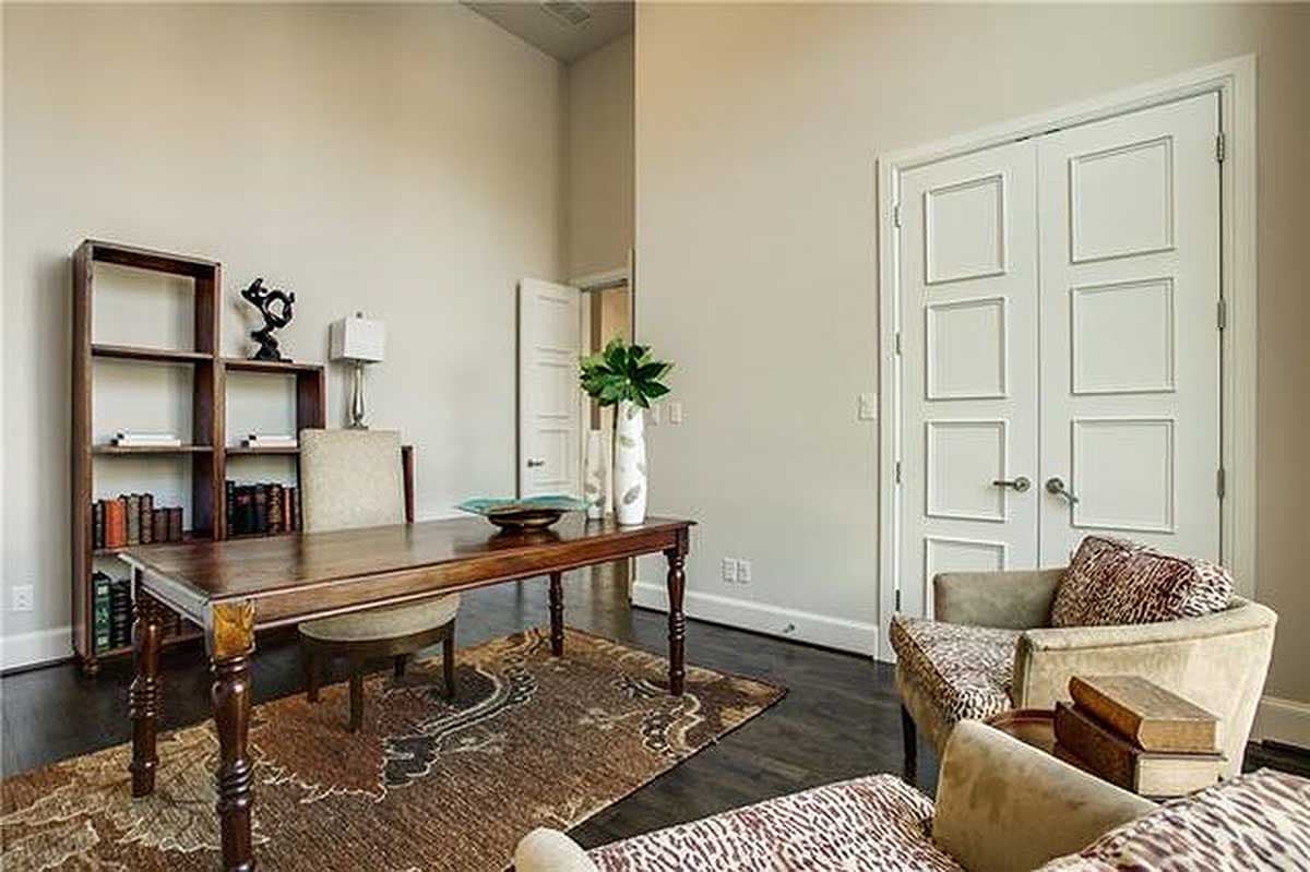 Home office with wooden desk, bookcase, and double doors with panel details.