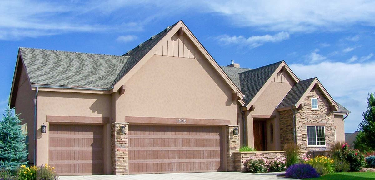 House plan exterior: stucco finish, three-car garage with wood-look doors, stone accents, and gabled roof.