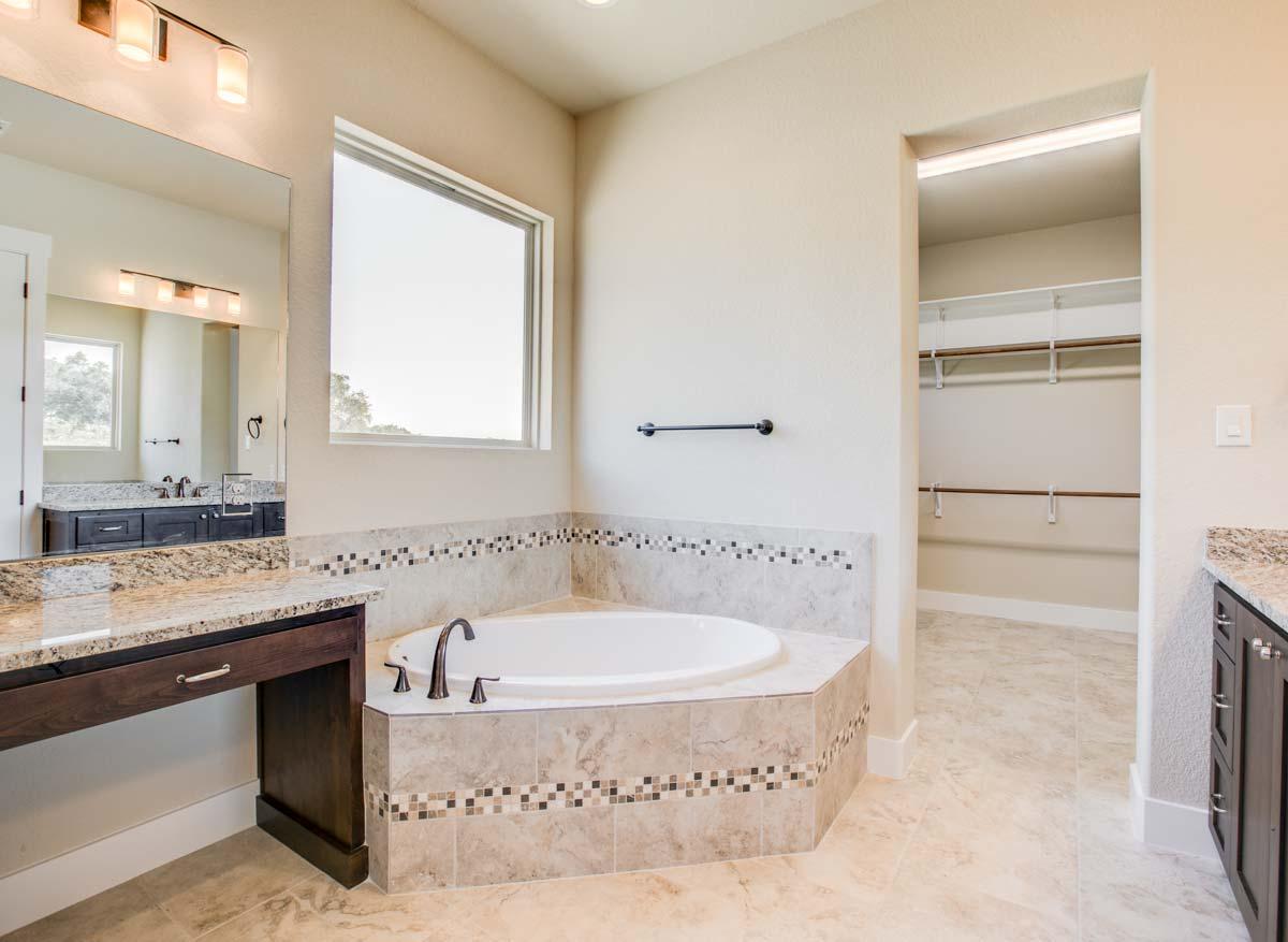 Bathroom with corner soaking tub, vanity, and walk-in closet.