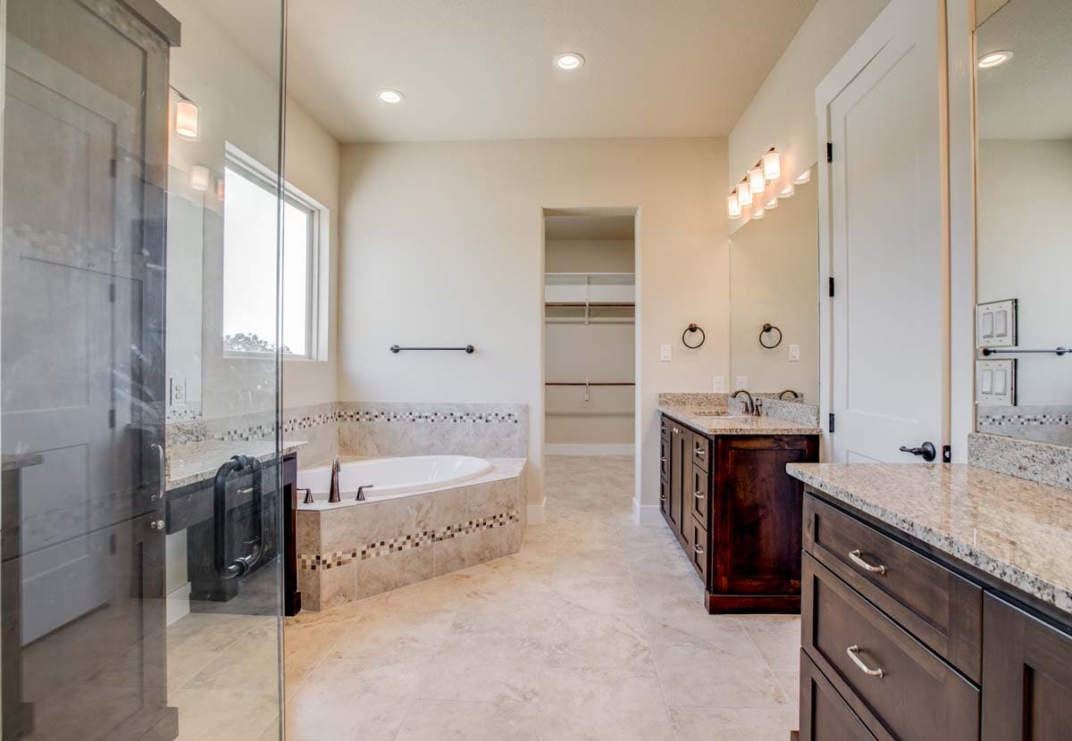 Bathroom with corner soaking tub, glass-enclosed shower, double vanity, and walk-in closet.