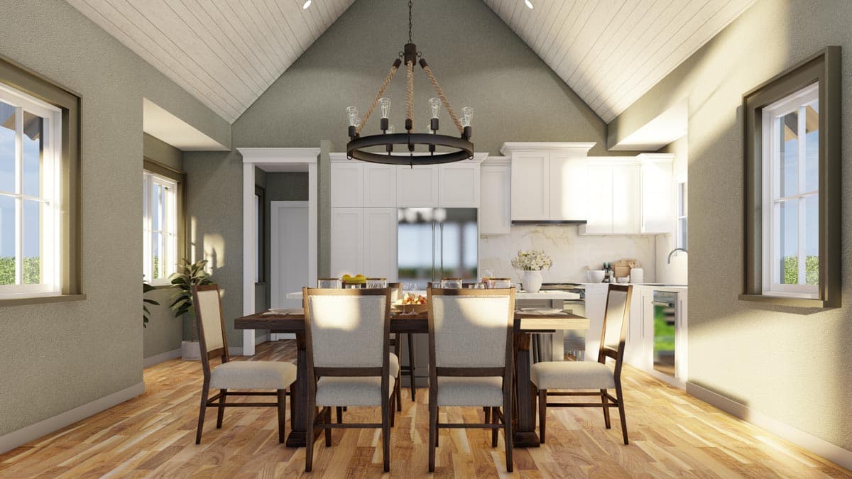Dining area with vaulted wood-paneled ceiling, chandelier, and view into white kitchen with island and stainless steel refrigerator.