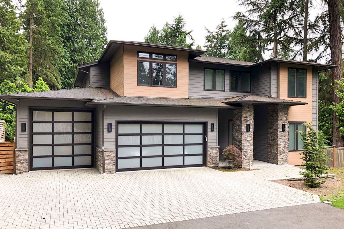 Modern two-story house plan exterior with a covered entry, dual frosted glass garage doors, and stone accents.